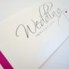 Silver and white foiled script wedding invitation with fuchsia pink flat ribbon