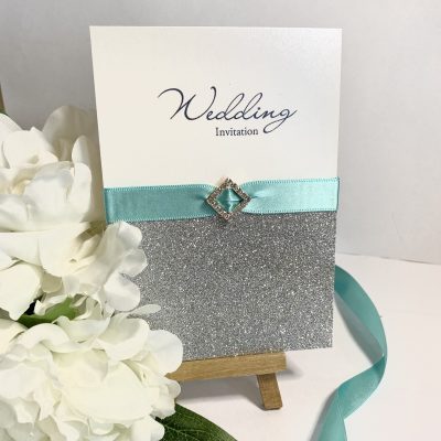 Concertina invitation with teal ribbon and diamond buckle