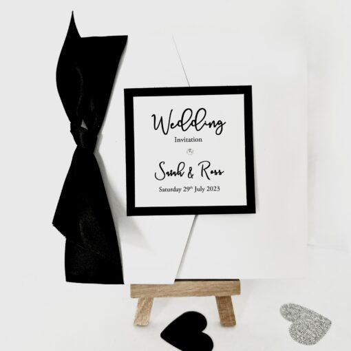 Crisp white pocketfold invitation with oversized black bow