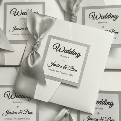 Crisp white pocketfold invitation with oversized bow